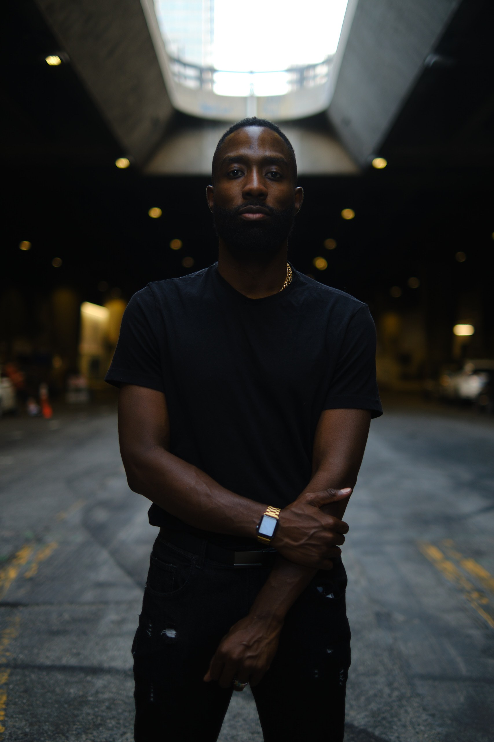 Dr. Charles Opong in black, arms crossed, standing in a Los Angeles underpass